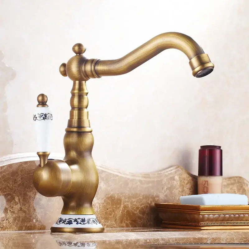 Decorbites antique brass kitchen sink faucet with ornate detailing and white ceramic handle with black floral patterns