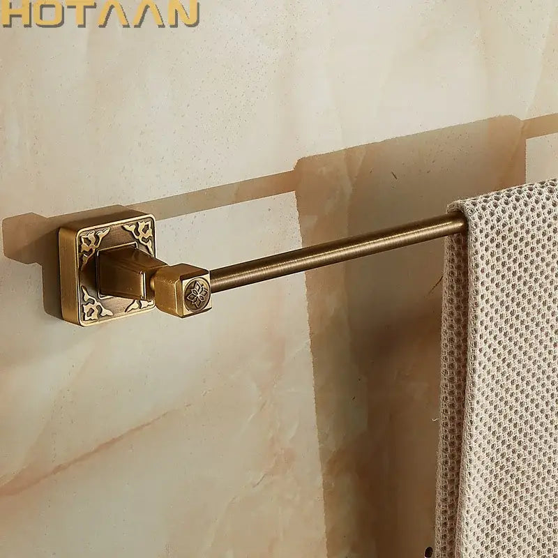 Antique brass single towel bar with ornate square wall mount and decorative floral engraving for bathroom use