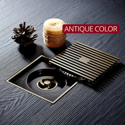 Antique brass square floor drain strainer with slatted grate and central turbine design for brass square bath use