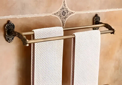 Antique bronze carved aluminum double towel rack with ornate scrollwork holding two off-white textured towels