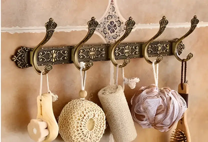 DecorBites antique bronze carved aluminum bathroom hook set with five ornate wall-mounted hooks holding bath accessories