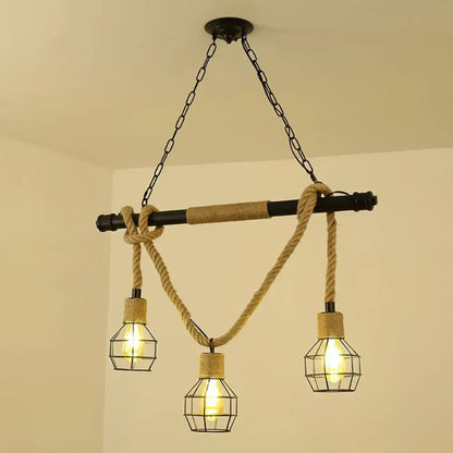 Decorbites™ antique iron hanging island light in black features industrial black pipe with three cage bulbs and hemp rope accents