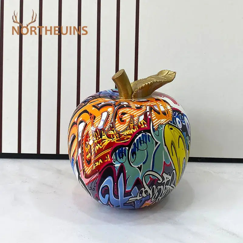 Vibrant decorbites apple figurines sculpture with golden stem featuring bold orange blue yellow and red graffiti art designs