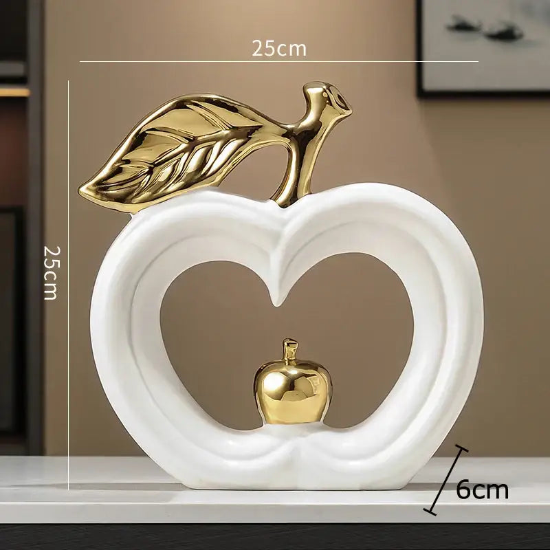 White ceramic decorbites apple sculpture with gold leaf and inner heart cutout holding miniature golden apple