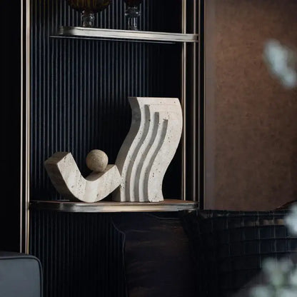 Cream-colored decorbites archway shape travertine sculpture figurine with flowing curves and a small spherical element