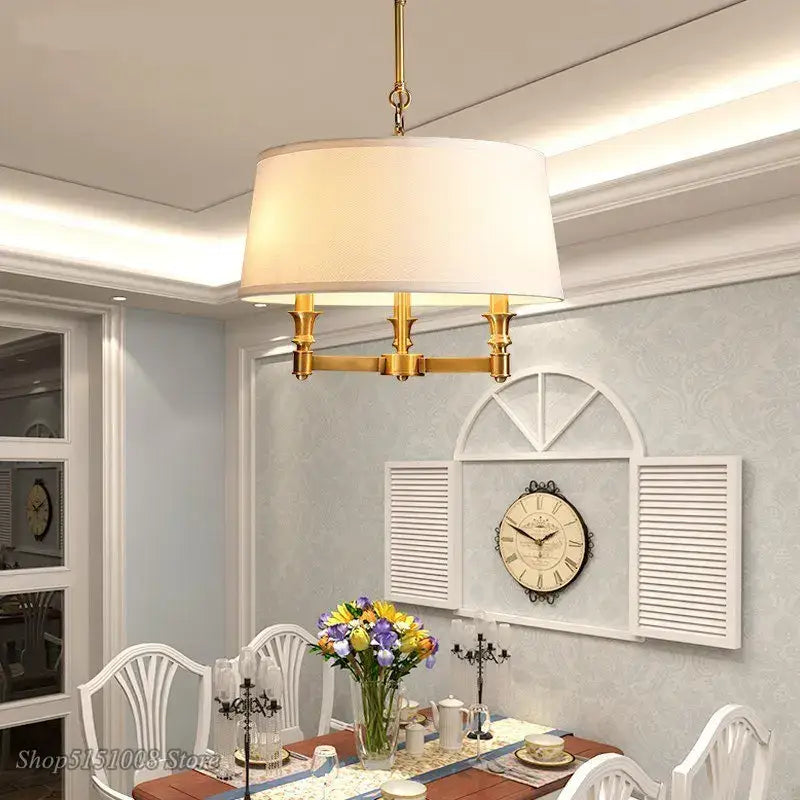 Gold-toned decorbites art deco pendant light with off-white fabric shade and three arms for dining room lighting