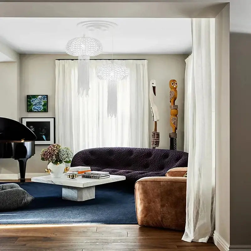 Dark purple tufted velvet sofa with plush surface and rounded backrest shown with decorbites art deco dimmable chandelier lighting