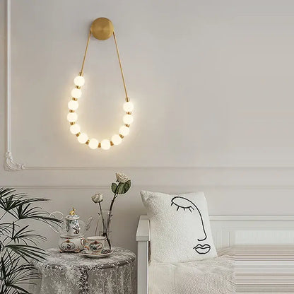 Gold-toned decorbites art deco glass led wall sconce with circular top and glowing spherical bulbs for bedroom lighting