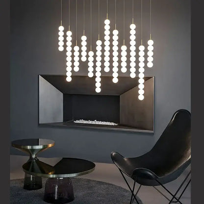 Decorbites art deco pendant light with vertical strands of glowing white glass pingpong bulbs on gold chrome cords