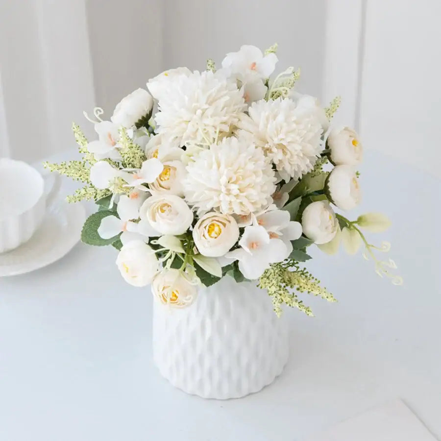 A delicate decorbites artificial hydrangea tea rose bouquet of white flowers with yellow centers in a white ceramic vase