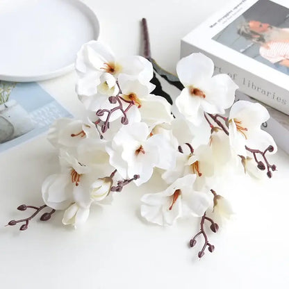A cluster of white decorbites artificial orchid magnolia flowers with delicate petals and brownish stems in a natural bouquet