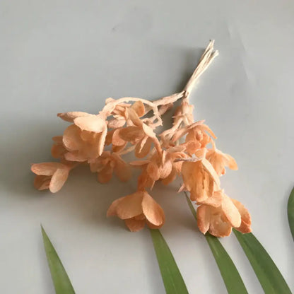 A delicate cluster of peach-colored artificial plants with slender stems from decorbites artificial plants green grass collection