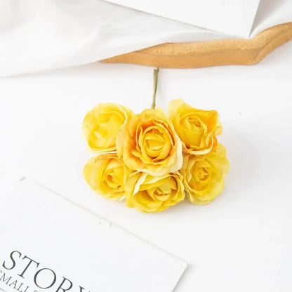 A cluster of five yellow decorbites artificial rose bouquet with delicate petals and green stems for home decor and weddings