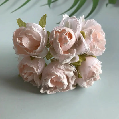 A delicate cluster of pale pink decorbites artificial roses with glitter accents and green ribbon stems for bridal use