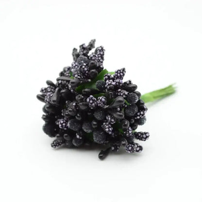 A cluster of black glittery decorbites artificial stamen flowers with subtle purple speckles and green stems for decor