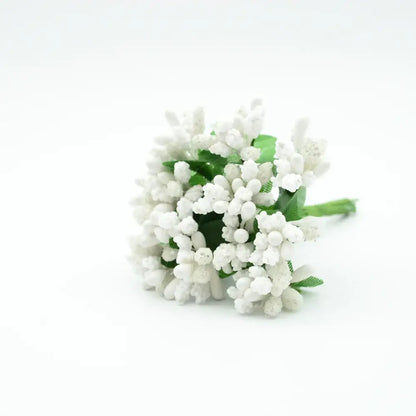 A delicate cluster of white decorbites artificial stamen flowers with green stems made from textured synthetic material
