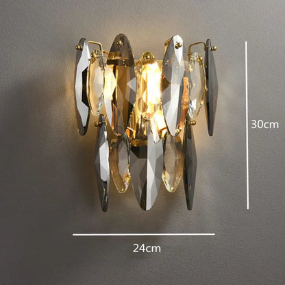 A modern decorbites ash crystal wall sconce with clear and smoky gray faceted shards held by gold metal fixtures