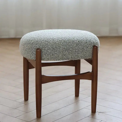 Round cushioned makeup bench with textured light gray fabric seat and sturdy ash wood legs by decorbites ash wood