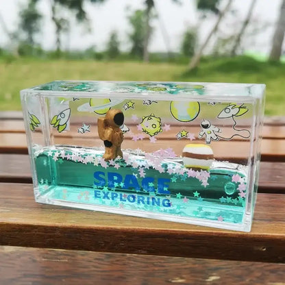 Clear acrylic decorbites astronaut drift keychain with golden astronaut, floating planets, teal liquid, and pink stars inside