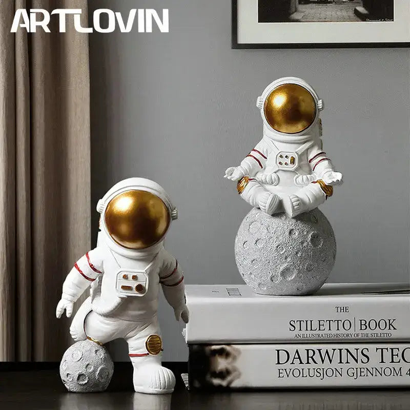 White decorbites astronaut figurine abstract sculpture with gold helmets sitting on textured moon base for modern decor