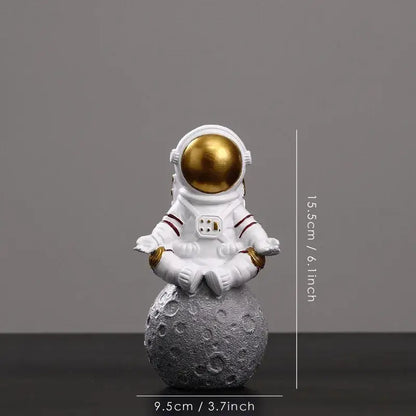 Decorbites astronaut figurine abstract sculpture in white with gold helmet seated in meditation on textured gray moon surface