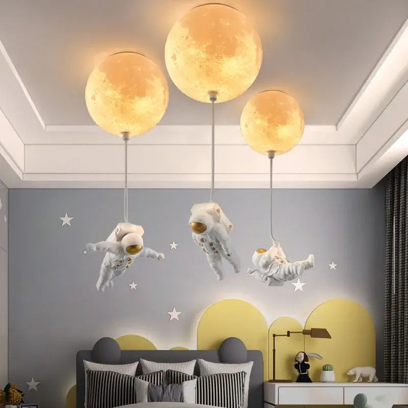 Three glowing textured moon-shaped pendant lights in the decorbites astronaut globe ceiling light for kids room