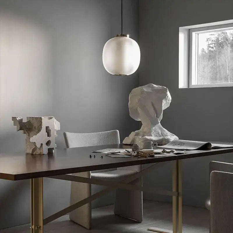 A minimalist white spherical pendant light with frosted glass shade complements decorbites black glass ball table light design