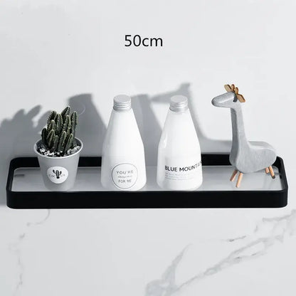 Black glass decorbites bathroom shelf corner rack with glossy finish holding white bottles and a small potted cactus
