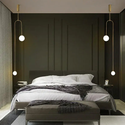 Modern gold-toned decorbites black gold chandelier pendant with spherical bulbs hanging symmetrically above bed