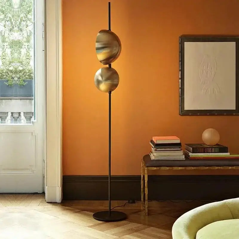 A sleek decorbites black gold led floor lamp with two polished brass spheres on a slender black pole