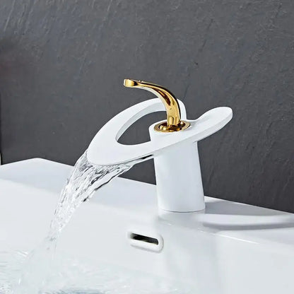 A modern white ceramic waterfall basin faucet with a sleek curved spout and gold-toned handle by DecorBites™