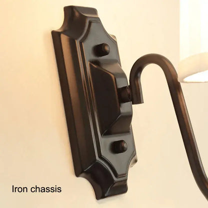 Dark bronze decorbites black iron wall lamp with ornate rectangular chassis and curved arm for elegant living spaces