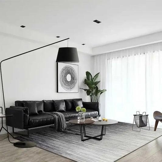 Black leather sectional sofa with modern design and plush cushions beside a sleek black decorbites led floor lamp