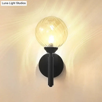 Modern black metal wall sconce with amber clear textured glass globe for bedroom lighting
