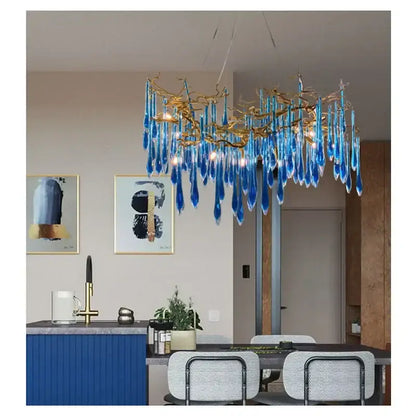 A decorbites blue crystal chandelier with gold branching arms and teardrop crystals for dining room lighting