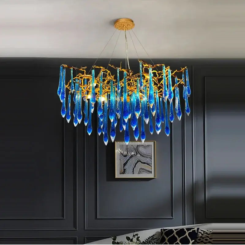 A decorbites blue crystal chandelier featuring golden branching arms and teardrop crystals for dining room use