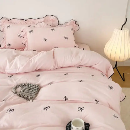 Pink satin DecorBites™ bow embroidery bedding set with ruffles features elegant black bow embroidery and ruffled edges