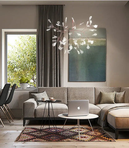 Silver laptop with minimalist design and apple logo on white table next to decorbites branch design nordic chandelier rose gold black