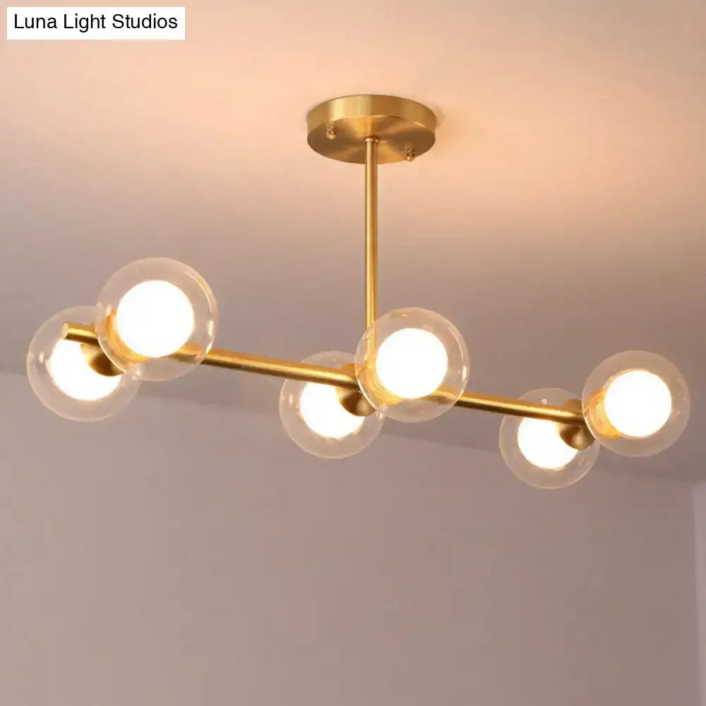 DecorBites brass finish linear island pendant with six white clear glass globe shades in a modern postmodern style
