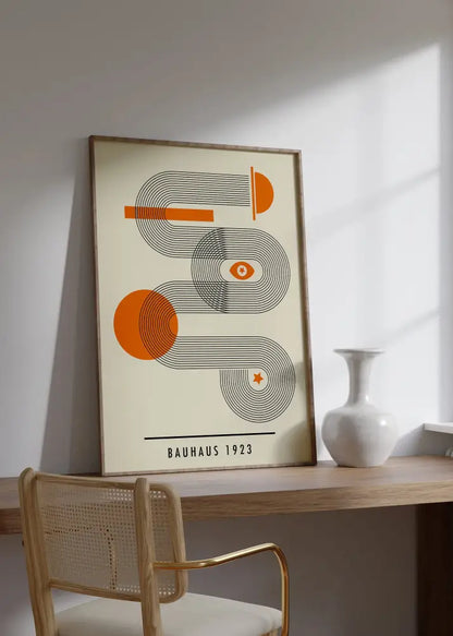 A mid century bauhaus framed poster with orange and black geometric wall art on cream background in a light wood frame