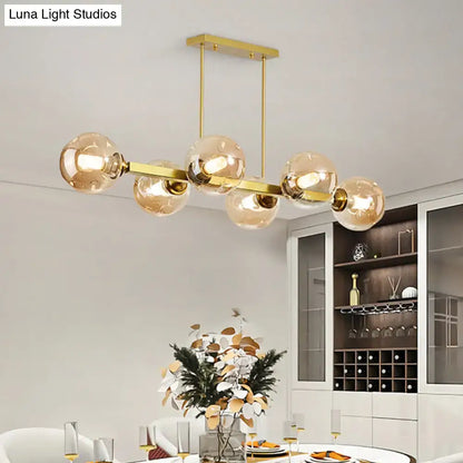 Gold-toned decorbites pendant light with five amber glass globes and sleek metallic frame features stylish island lighting