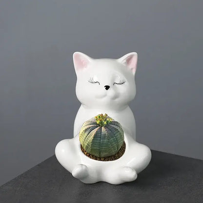 White ceramic decorbites cartoon kitten planter with closed eyes holding green striped cactus for succulents