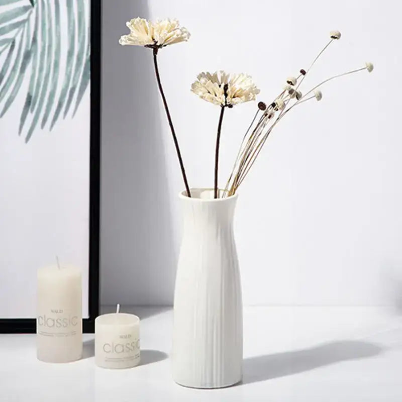 White ceramic-look plastic vase imitation with vertical ribbed texture holding dried flowers for home and garden decor