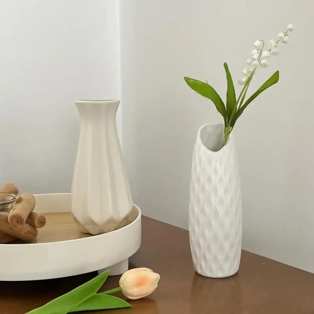 White ceramic-look plastic vase imitation with textured diamond pattern holding white lily-of-the-valley flowers for decor