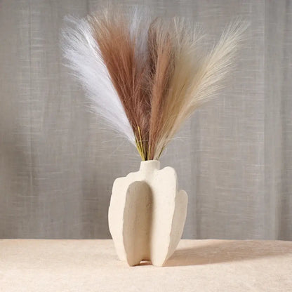 Cream-colored sculptural ceramic sea vase with modern abstract design holding white and beige pampas grass nordic modern decor