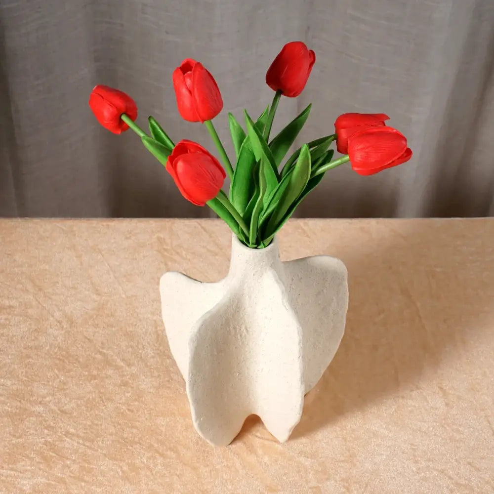 White ceramic sea vase with abstract wing-like design holding vibrant red tulips for nordic modern decor