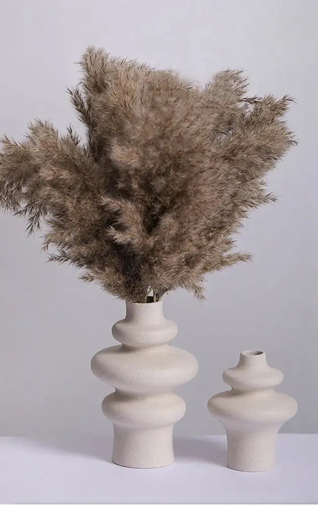 Cream-colored ceramic vase with stacked rounded segments and beige pampas grass for modern home decor by decorbites