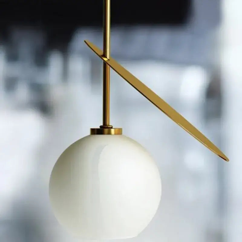 A sleek decorbites cherry glass pendant light with a matte white spherical shade and gold-toned metal accents