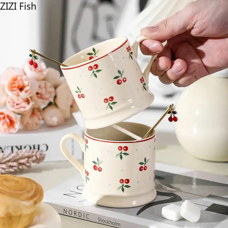 Cream-colored lovely cherry pattern porcelain coffee mugs with gold spoons ideal for afternoon tea use