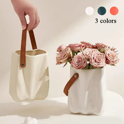 Cream-colored chic ceramic vase with textured wavy surface and brown leather handle for home decoration